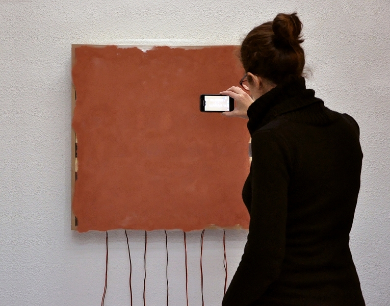 Abelardo G. Fournier, <em>Mineral Vision,</em> 2015. <em>Mineral Vision</em> consists of a screen made of copper dust held by a wood structure. When the surface is observed through the lens of a digital device—e.g., a smartphone or tablet—a message, buried in the copper and quoted from Roman historian Tacitus, becomes visible: “Where they create a desert, they call it peace.”